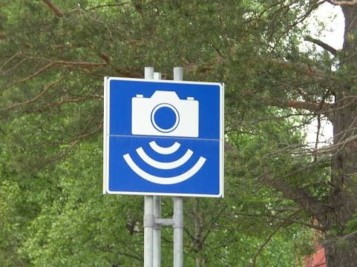 An automatic speed camera Fotoboks and its blue warning sign on a rural road in Norway
